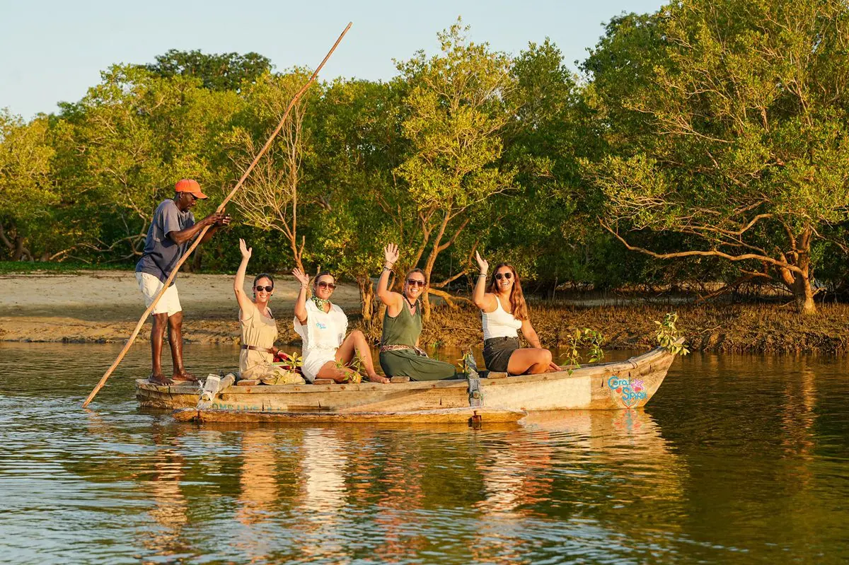 Travellers taking a traditional boat through the mangroves at sunset